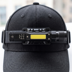 The compact right-angle flashlight mounted on an adjustable headlamp strap and worn over a black baseball cap.