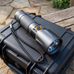 A high-power aluminum LED flashlight with a lanyard resting on a black protective equipment case outdoors.