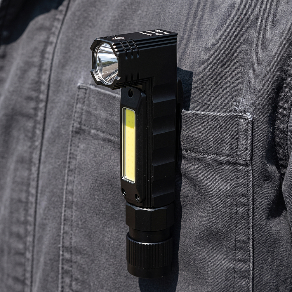 A black right-angle LED flashlight clipped securely to a worker's jacket pocket for hands-free illumination.