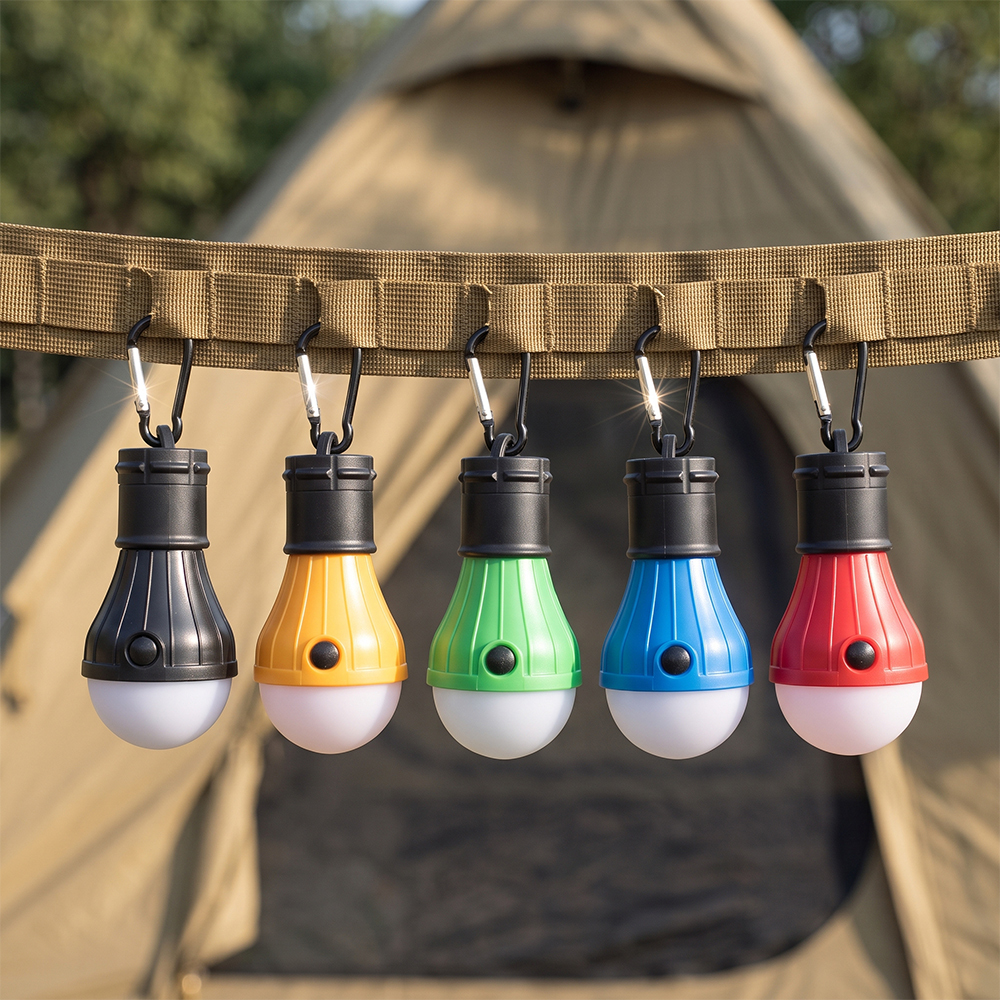 A row of five colorful mini LED bulb lights hanging with carabiners on a tactical strap in front of a camping tent.