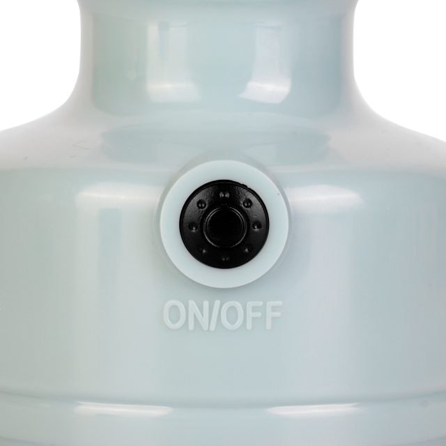A close-up view of the push button power switch on the light blue lantern base.