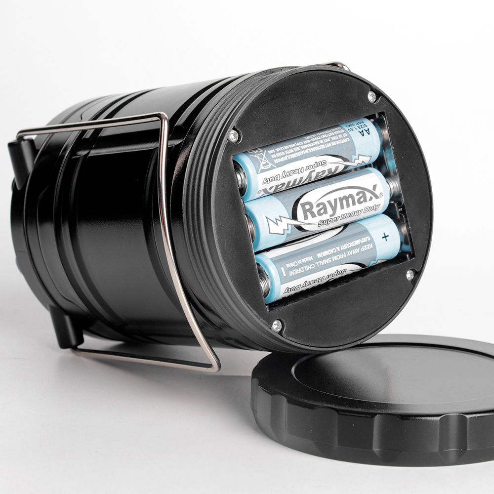 Close-up view of the opened bottom compartment showing three AA batteries inside the collapsible lantern.