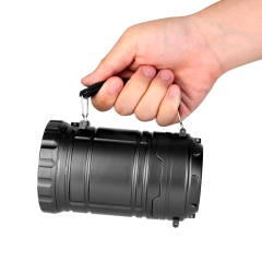 A hand holding the dark grey camping lantern horizontally using the top folding handle like a flashlight.