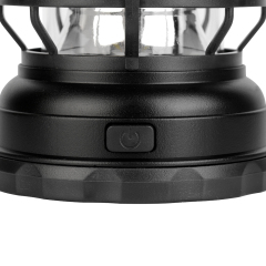 Close-up view of the power switch button on the base of the black camping lantern.