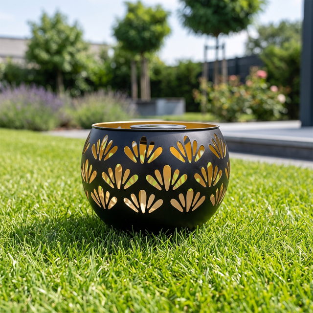 A black hollowed-out solar garden light placed on a green garden lawn during daytime.