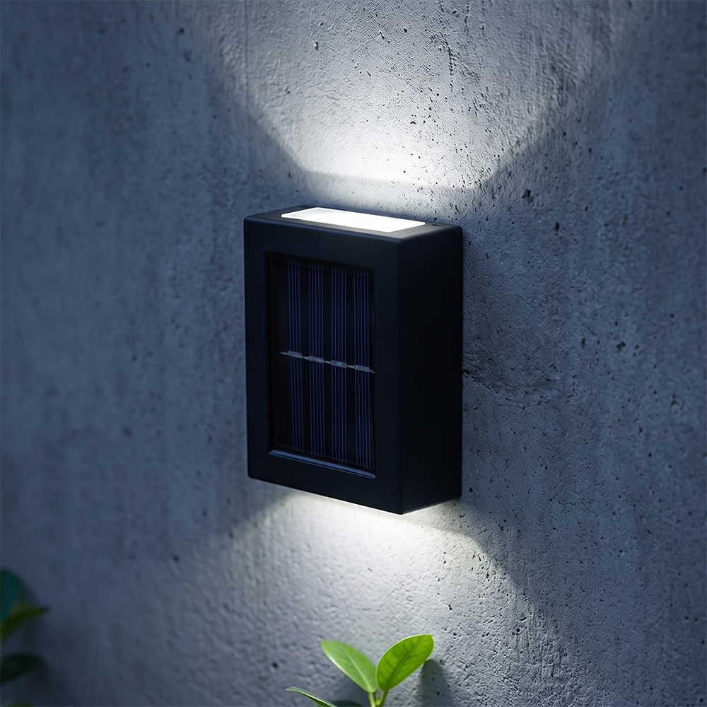 A black solar fence light glowing with cool white up and down light on a textured surface at night.