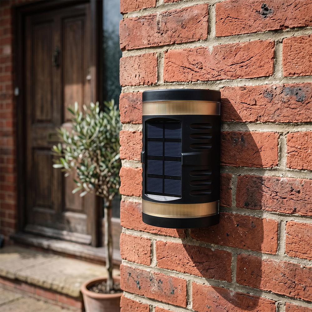 A black cylindrical solar shadow wall light mounted on a red brick wall of a house porch during daytime.