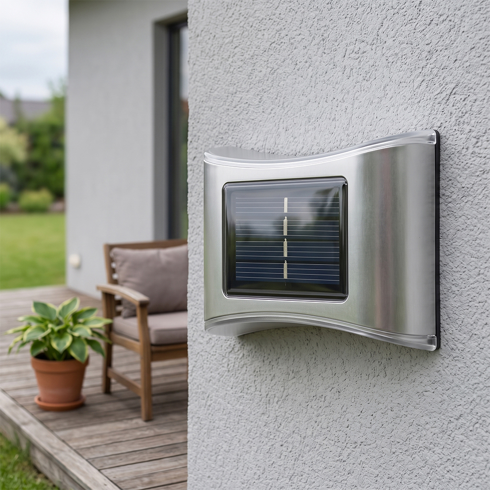 A stainless steel solar up and down wall light mounted on a white exterior wall next to a patio.