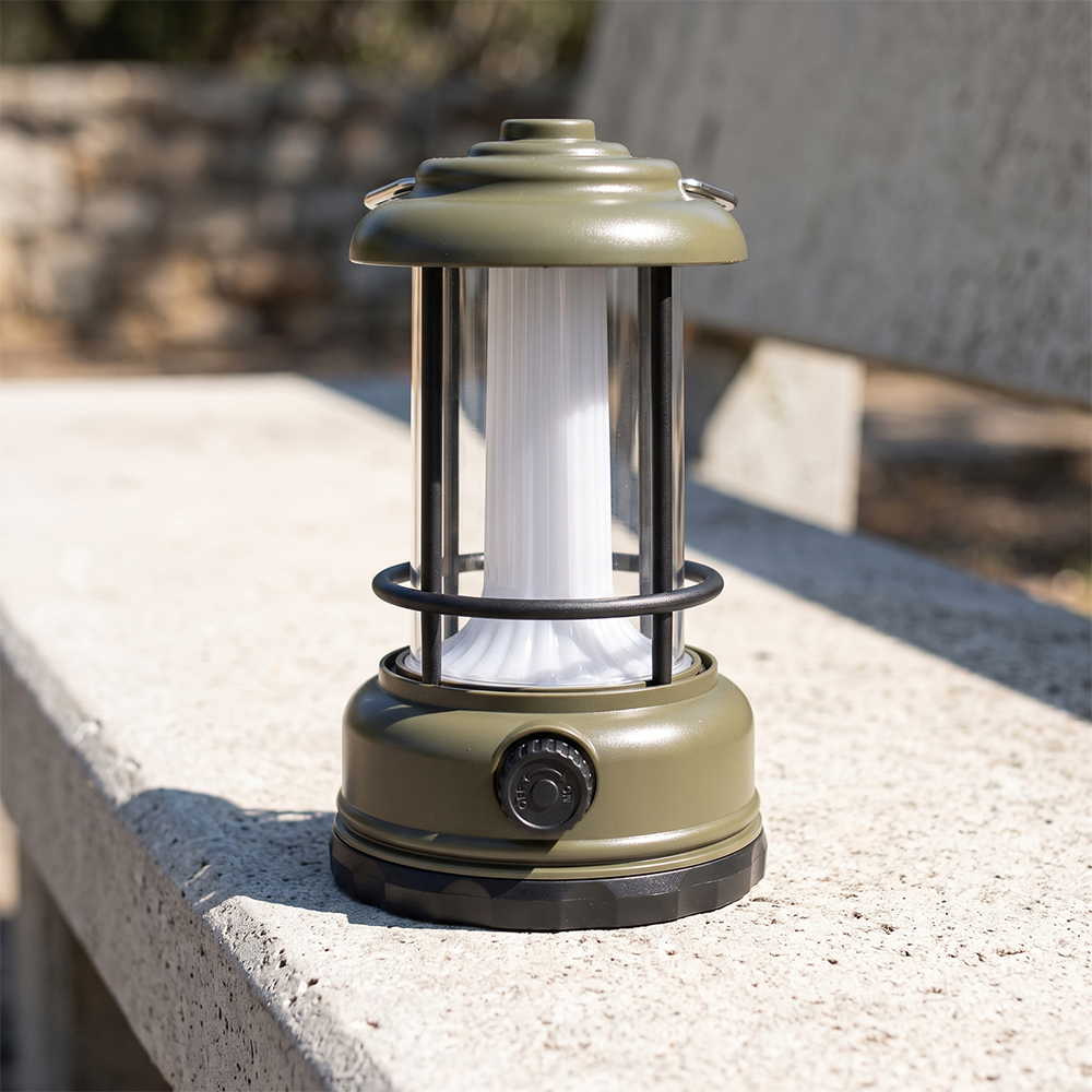 An army green vintage LED camping lantern sitting on an outdoor stone bench on a sunny day.