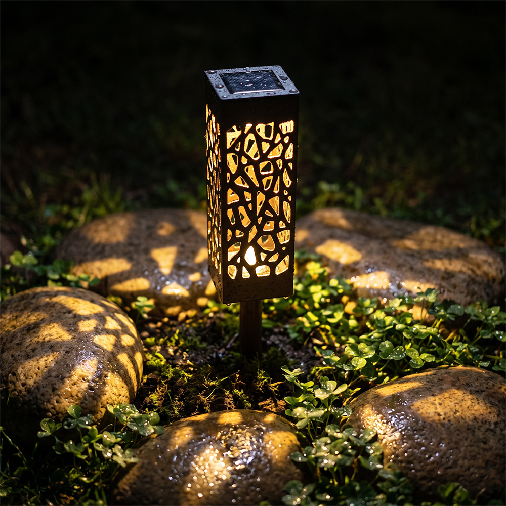 Close-up of a solar stake light casting warm geometric shadow patterns on cobblestones and green foliage.