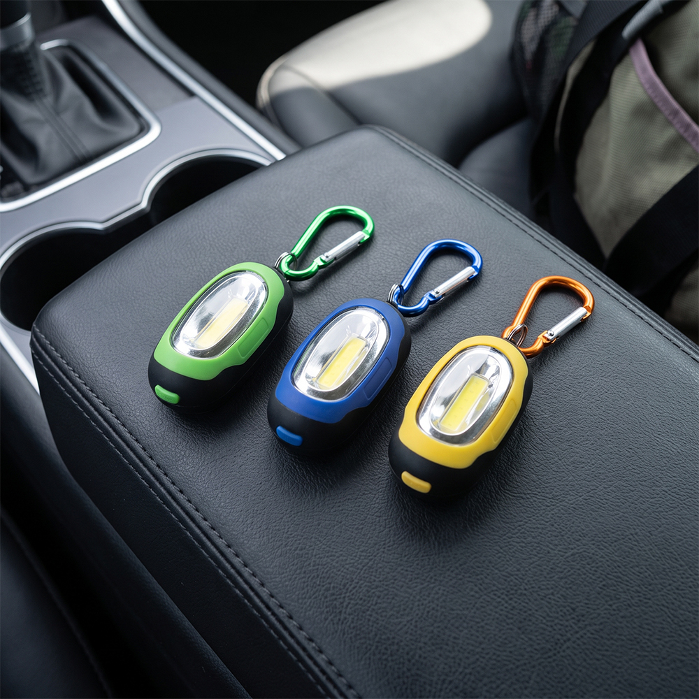 Three colorful mini COB LED keychain lights lying on a leather car armrest for automotive EDC.