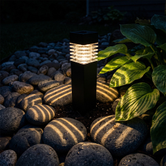 Close-up of a solar bollard light casting circular warm shadow patterns on river cobblestones.