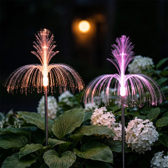 Close-up of orange and purple solar optical fiber fountain lights glowing brightly in a garden at night.