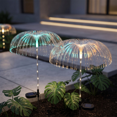 Solar optical fiber jellyfish lights with warm light reflections among monstera plants next to a set of stairs.