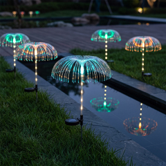 Solar optical fiber lights with glowing spheres illuminating the edge of a garden stream on a grass lawn at night.