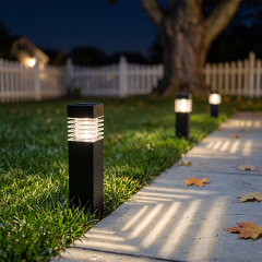 Solar pathway bollard lights lining a lawn and casting striped light patterns across a concrete walkway at night.