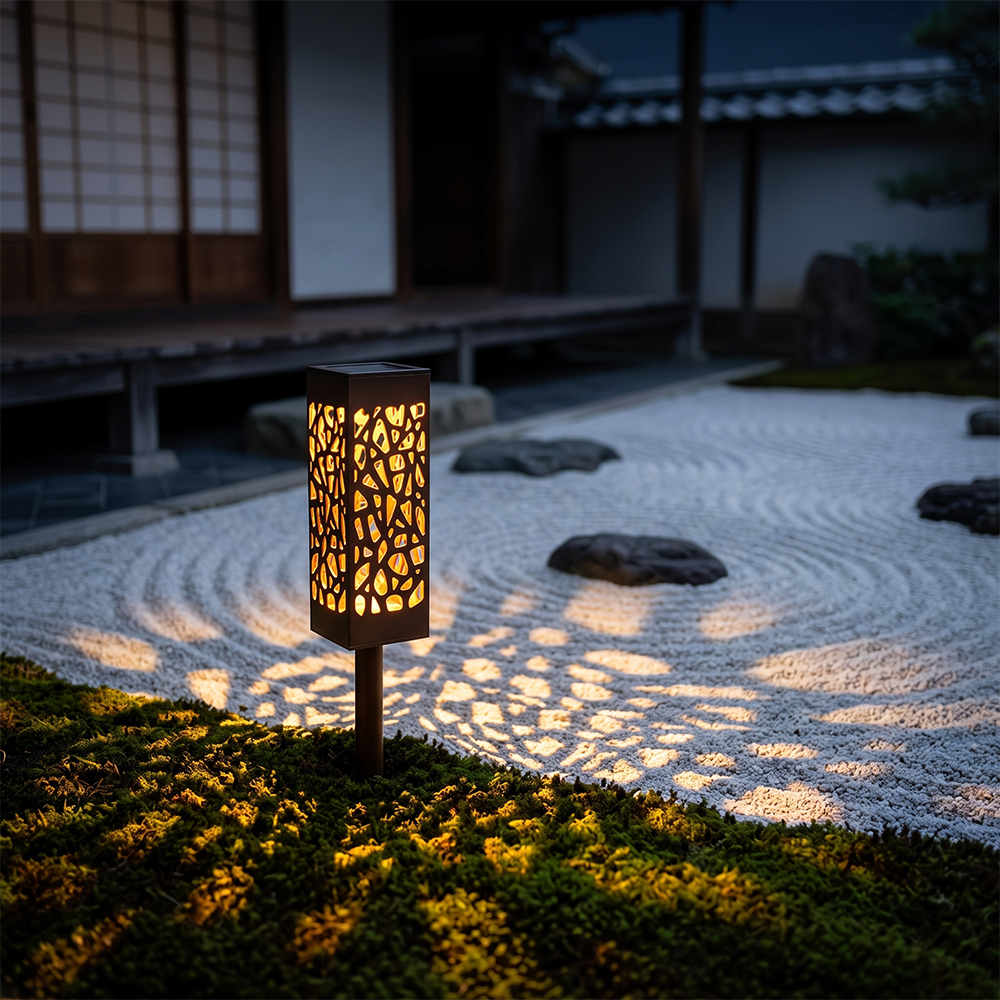 A solar pathway light illuminating a white gravel zen garden with decorative pattern light at night.