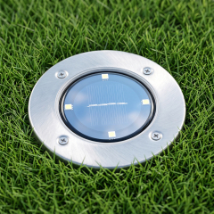 Top view of a stainless steel solar ground disk light installed flush in a green lawn.