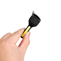 A hand holding a mini key-shaped COB LED keychain light to demonstrate its compact size.