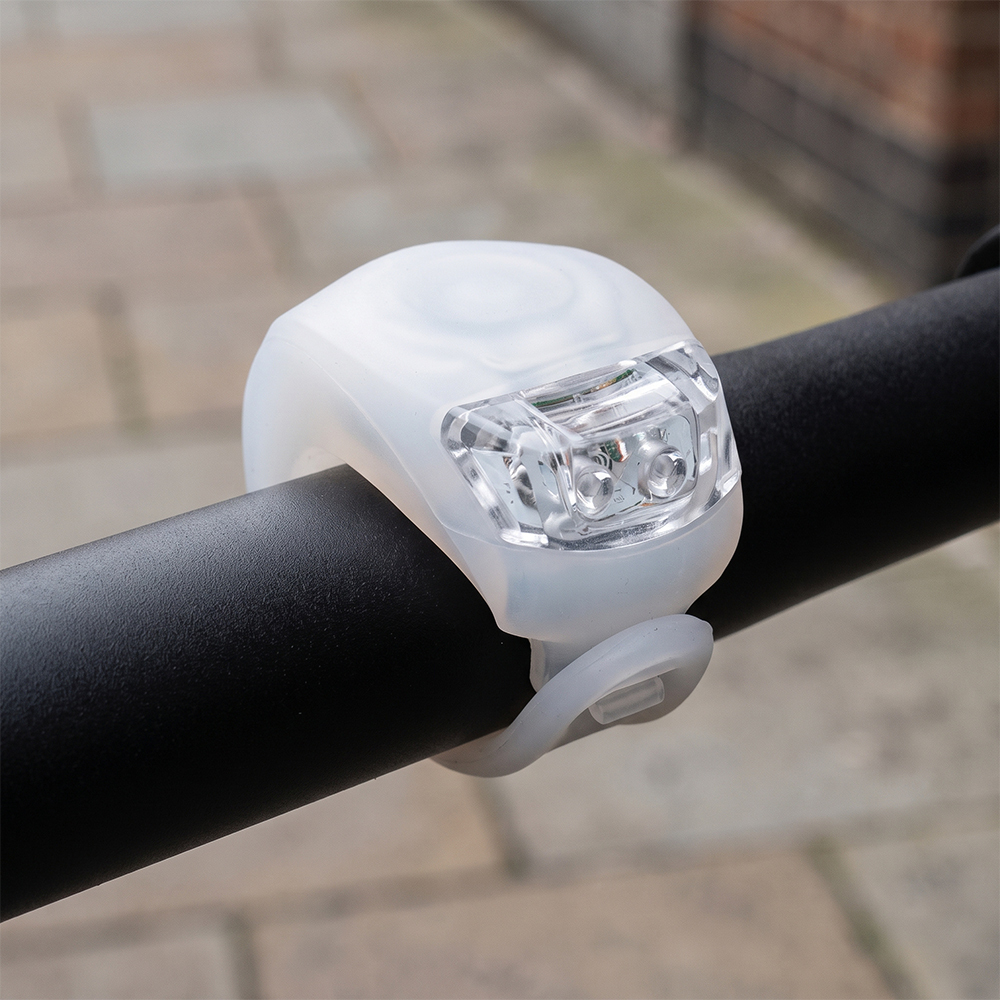 A clear translucent silicone LED bike light wrapped around a bicycle handlebar outdoors.