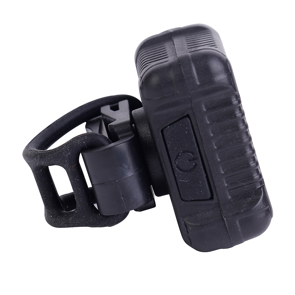 Side perspective of the COB LED bike light featuring a flexible silicone mounting strap and power button.