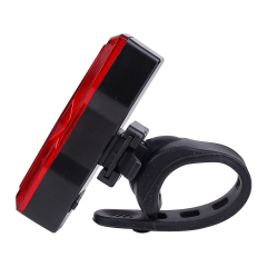 Side angled view of a red LED bike tail light with a silicone mounting strap.