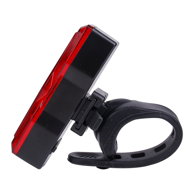 Side angled view of a red LED bike tail light with a silicone mounting strap.