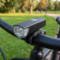 Rechargeable LED bicycle front light mounted on a bike handlebar in an outdoor park setting.