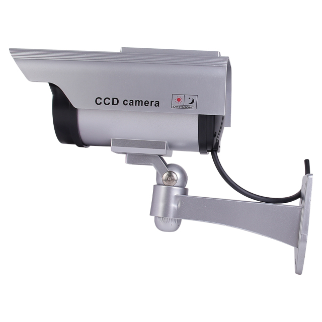 Side view of a silver dummy security camera showing the multi-axis wall bracket and connecting cable.
