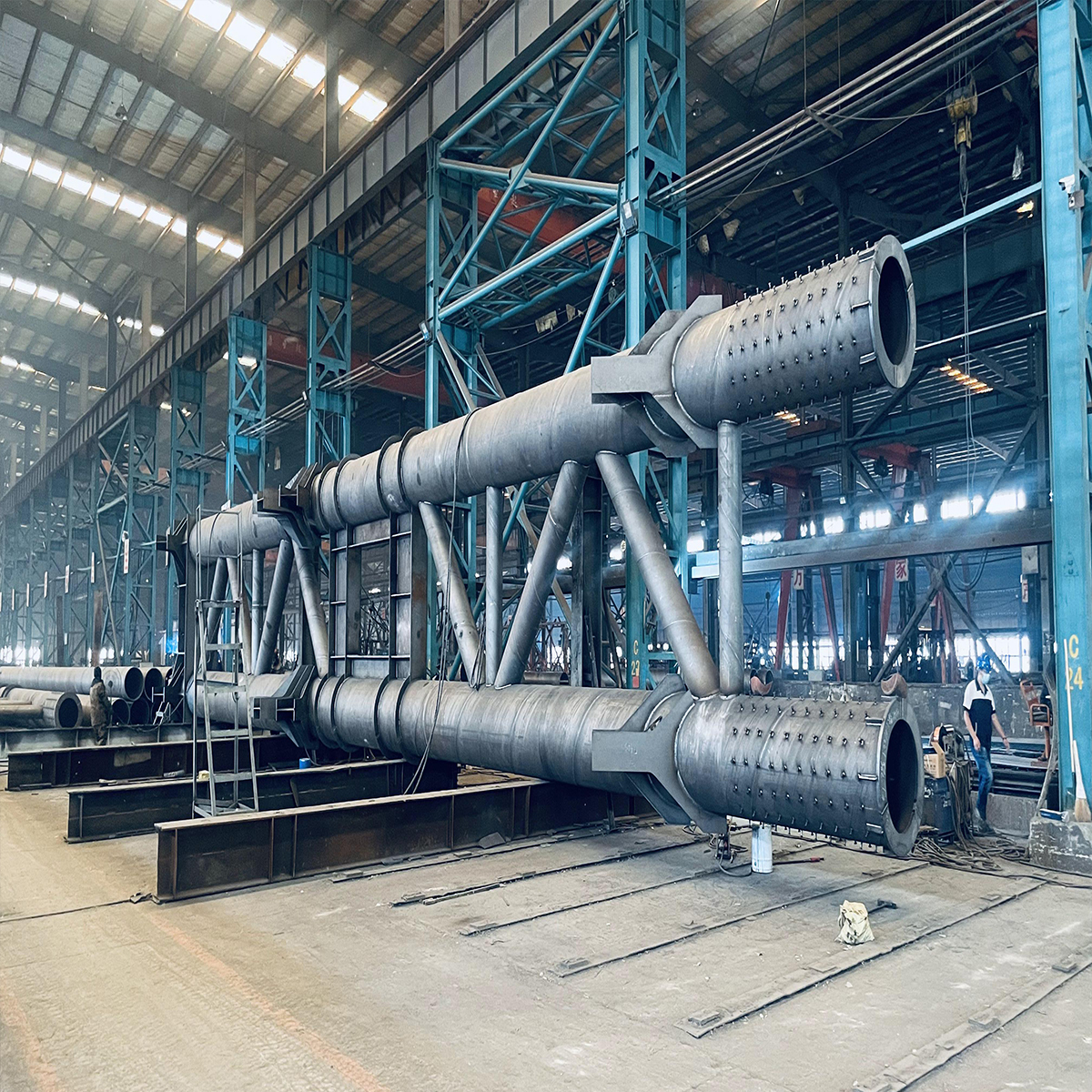 Fabrication of a heavy tubular steel truss assembly inside an industrial workshop