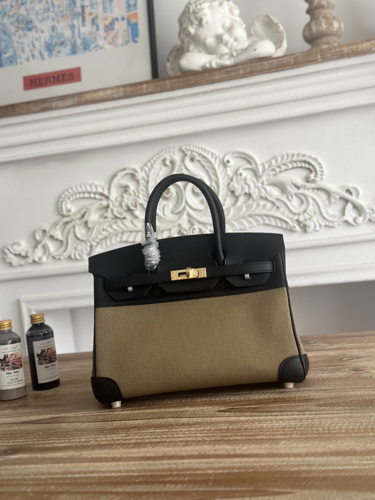 This Birkin-style tote bag features a military green canvas and black leather exterior, giving it a rugged yet retro look with a strong workwear feel.