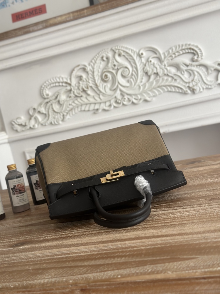 This Birkin-style tote bag features a military green canvas and black leather exterior, giving it a rugged yet retro look with a strong workwear feel.