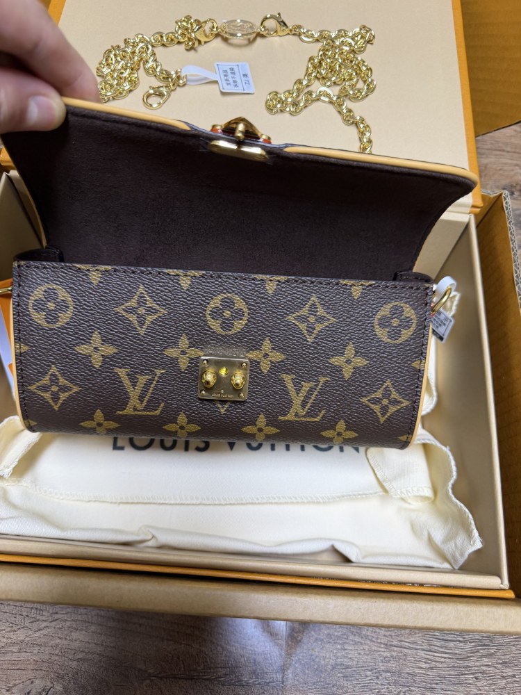 The Louis Vuitton LV East-West Mini Chain Bag (colloquially known as the "Mini Papillon") is crafted from the classic Monogram canvas.