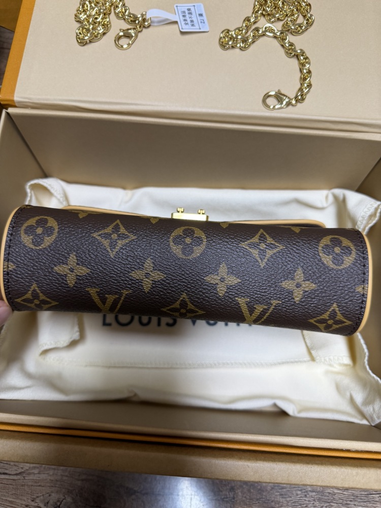 The Louis Vuitton LV East-West Mini Chain Bag (colloquially known as the "Mini Papillon") is crafted from the classic Monogram canvas.