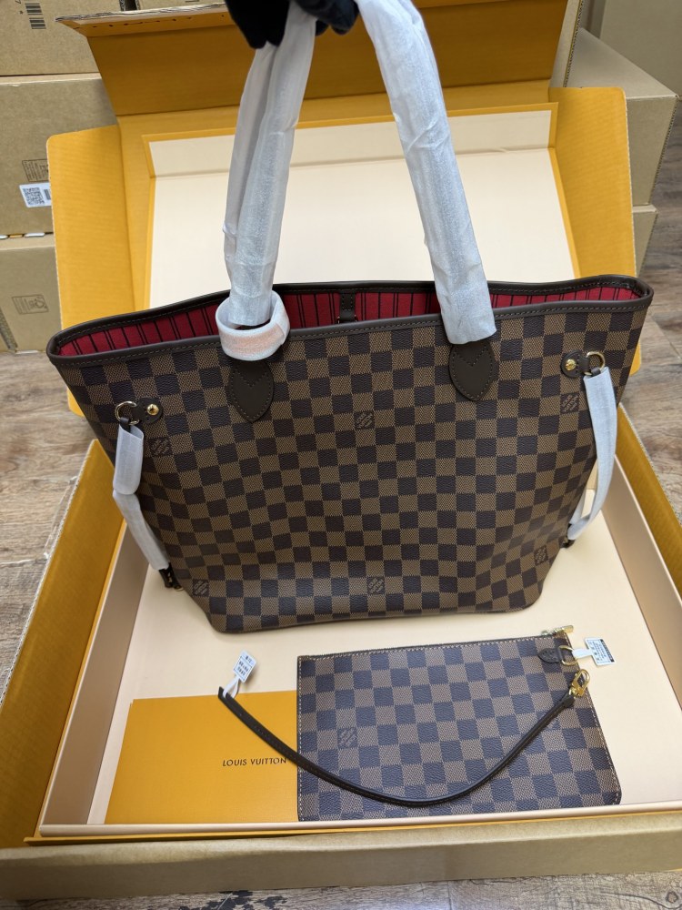 The Louis Vuitton Neverfull MM medium tote bag features the classic Damier Ebene brown checkered canvas, paired with the iconic red striped lining.