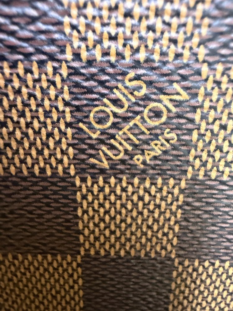 The Louis Vuitton Neverfull MM medium tote bag features the classic Damier Ebene brown checkered canvas, paired with the iconic red striped lining.