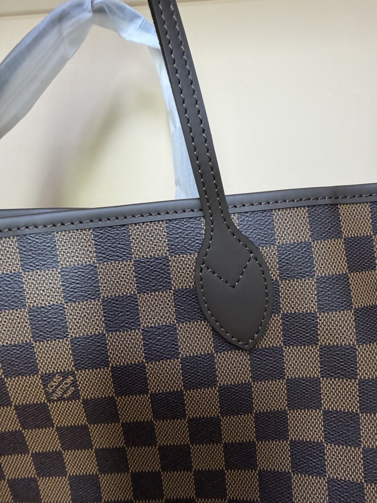 The Louis Vuitton Neverfull MM medium tote bag features the classic Damier Ebene brown checkered canvas, paired with the iconic red striped lining.