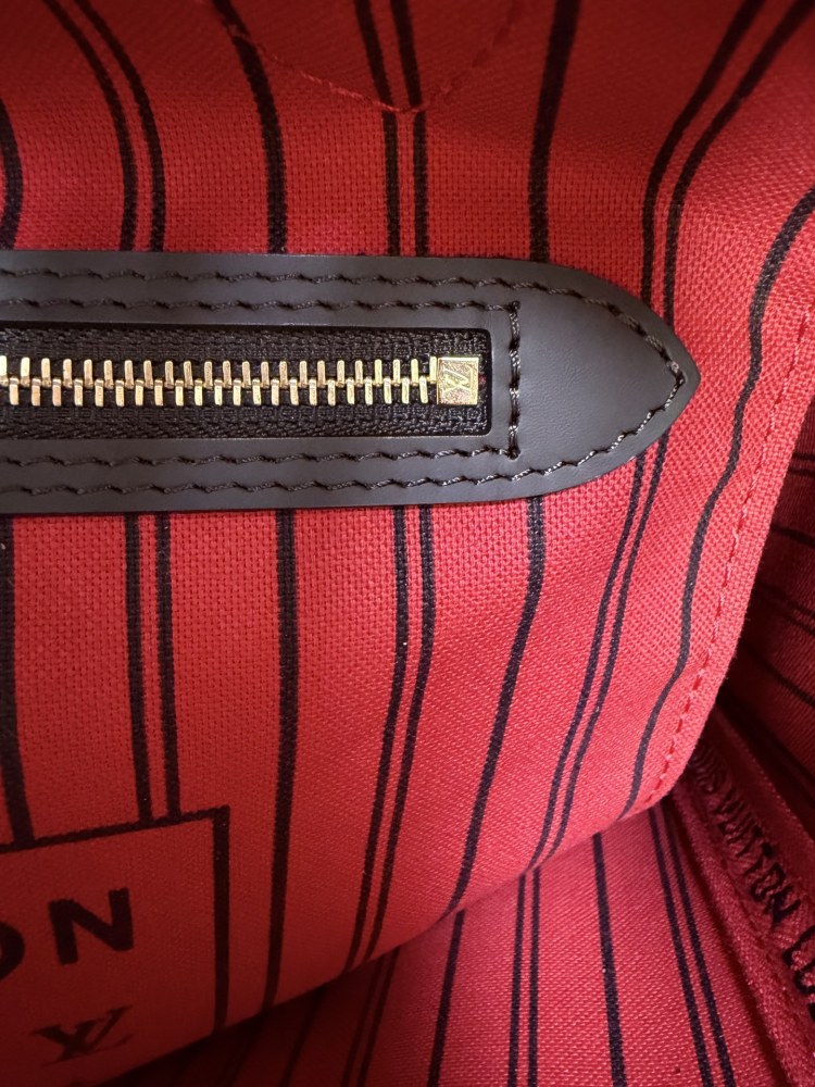 The Louis Vuitton Neverfull MM medium tote bag features the classic Damier Ebene brown checkered canvas, paired with the iconic red striped lining.