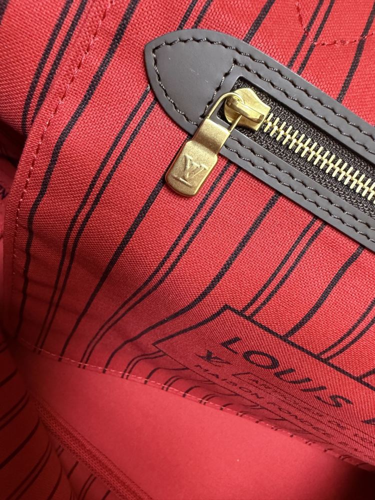 The Louis Vuitton Neverfull MM medium tote bag features the classic Damier Ebene brown checkered canvas, paired with the iconic red striped lining.