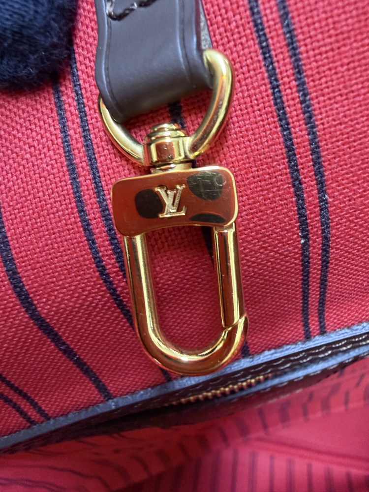 The Louis Vuitton Neverfull MM medium tote bag features the classic Damier Ebene brown checkered canvas, paired with the iconic red striped lining.