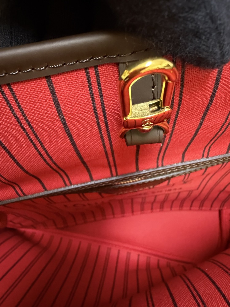 The Louis Vuitton Neverfull MM medium tote bag features the classic Damier Ebene brown checkered canvas, paired with the iconic red striped lining.