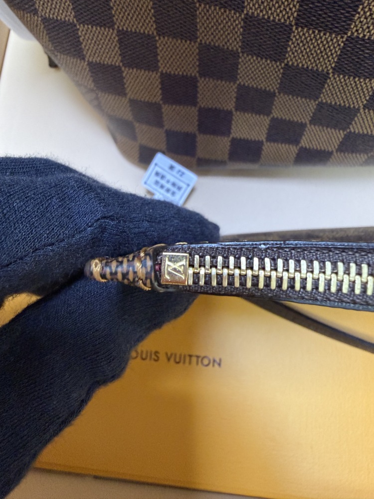 The Louis Vuitton Neverfull MM medium tote bag features the classic Damier Ebene brown checkered canvas, paired with the iconic red striped lining.