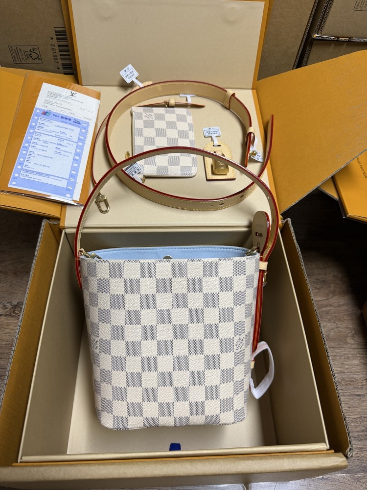 The Louis Vuitton Nano Bucket bag features the brand's classic Damier Azur white checkered canvas, paired with a light blue lining.