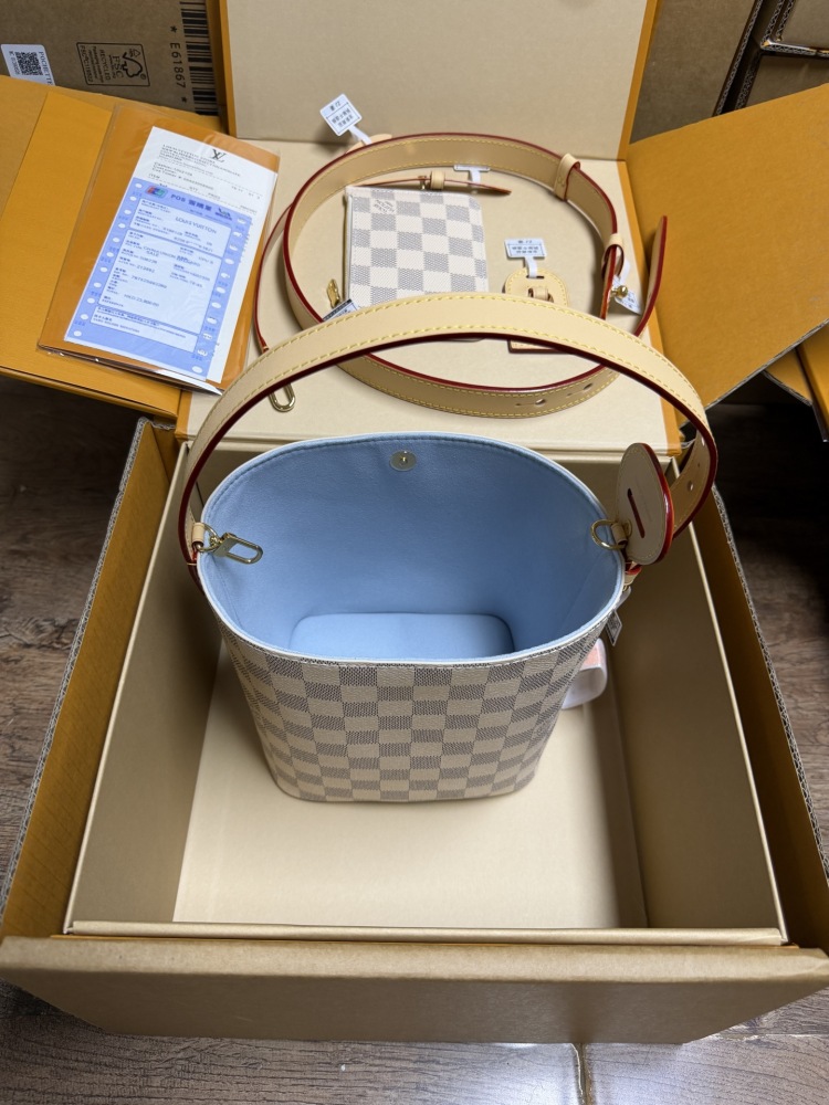 The Louis Vuitton Nano Bucket bag features the brand's classic Damier Azur white checkered canvas, paired with a light blue lining.