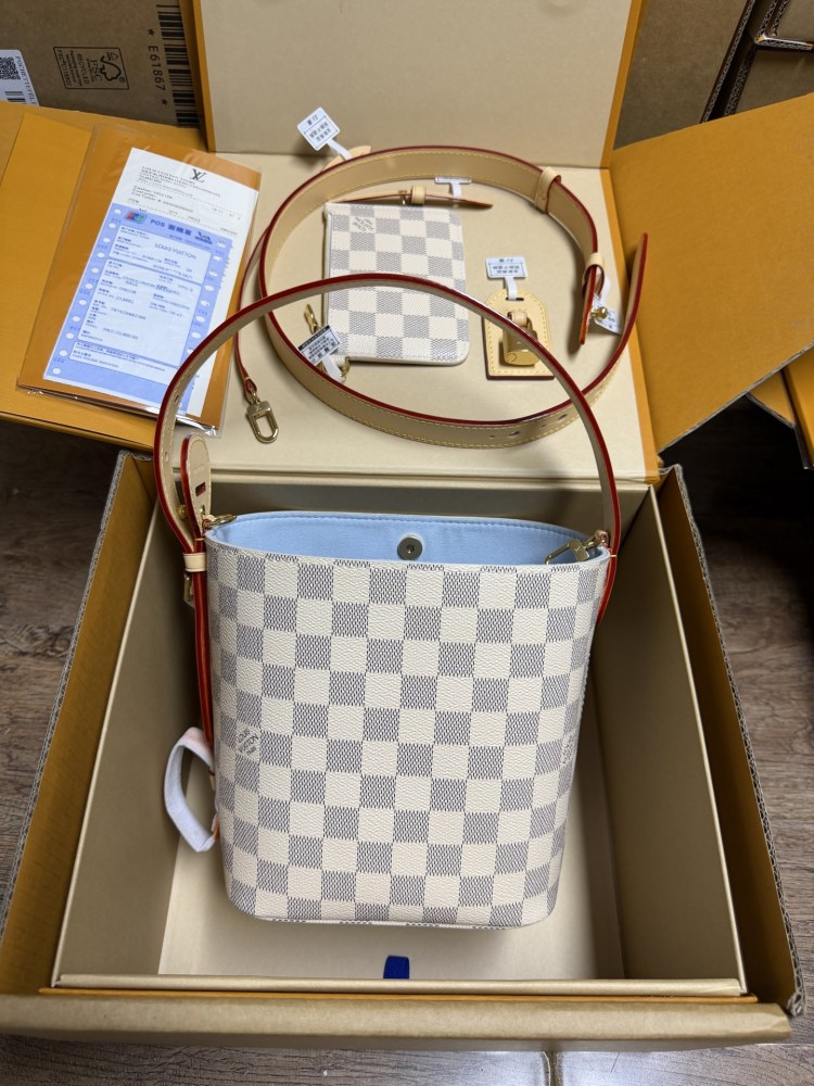 The Louis Vuitton Nano Bucket bag features the brand's classic Damier Azur white checkered canvas, paired with a light blue lining.