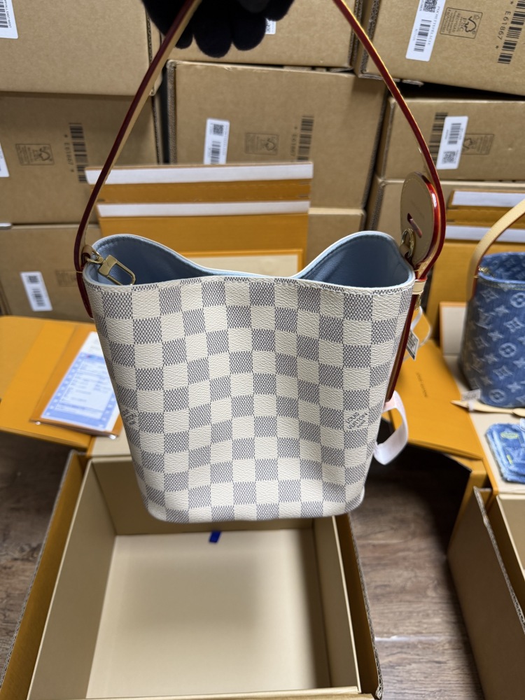 The Louis Vuitton Nano Bucket bag features the brand's classic Damier Azur white checkered canvas, paired with a light blue lining.