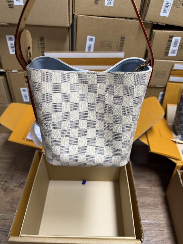 The Louis Vuitton Nano Bucket bag features the brand's classic Damier Azur white checkered canvas, paired with a light blue lining.