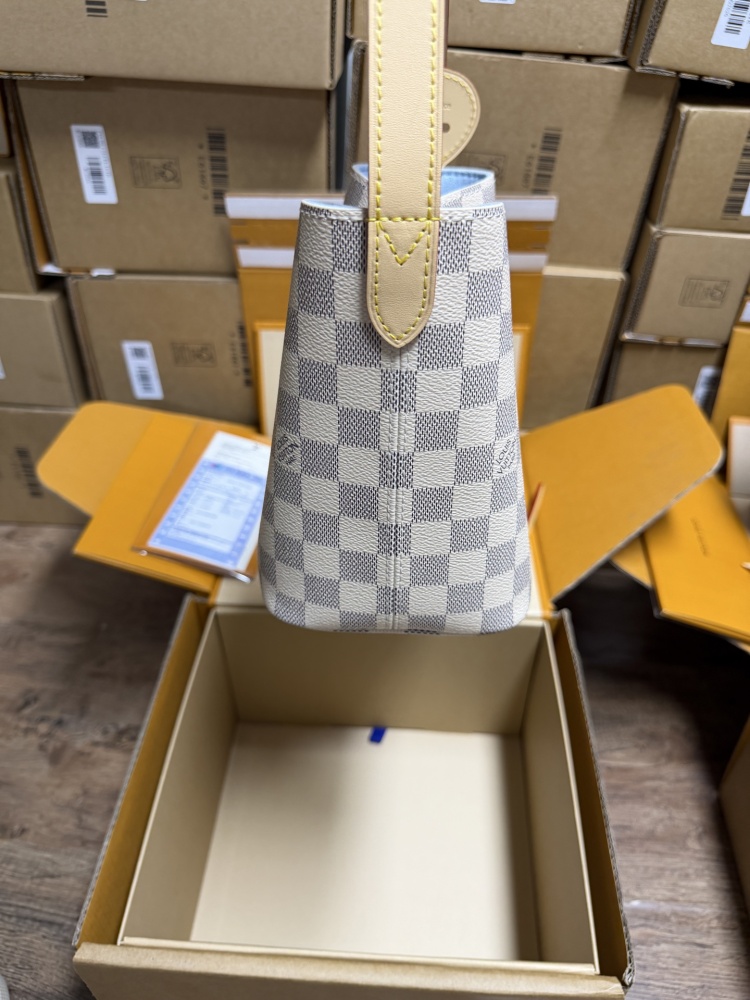 The Louis Vuitton Nano Bucket bag features the brand's classic Damier Azur white checkered canvas, paired with a light blue lining.