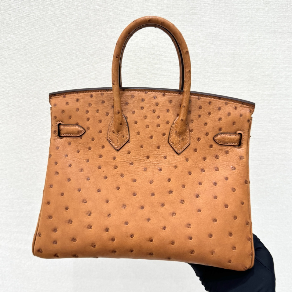 The Hermès Birkin 30 handbag in Ostrich leather—rendered in the "Gold" shade (also known as "Gold Brown" or "Caramel") and accented with silver hardware—is a classic model from the brand and a highly collectible, rare-skin edition.