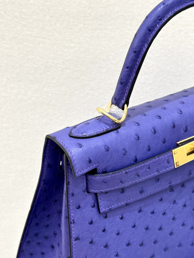 The Hermès Kelly 25 handbag in ostrich leather—rendered in a deep marine blue (gemstone blue / midnight blue) and accented with gold hardware—stands as a quintessential example of understated luxury among Hermès' exotic skins.